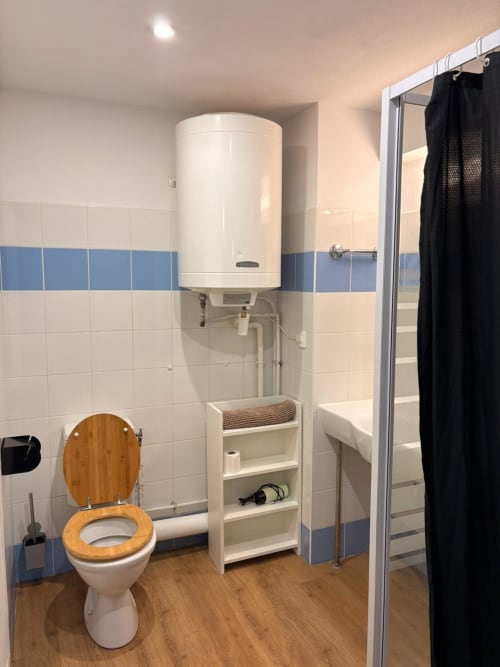 Salle de bain moderne du Studio 305 Le Clos d'Aix avec toilettes, douche, chauffe-eau, rangements et parquet