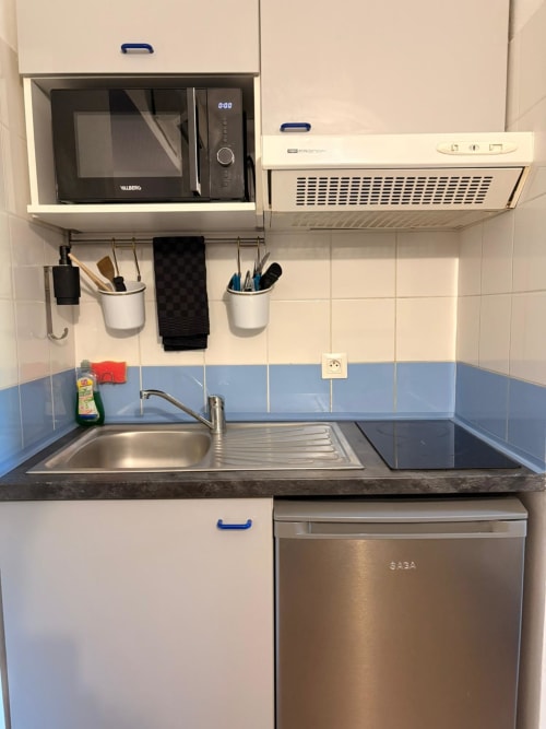 Kitchenette compacte du Studio 305 Le Clos d'Aix avec micro-ondes, cuisinière, évier et réfrigérateur