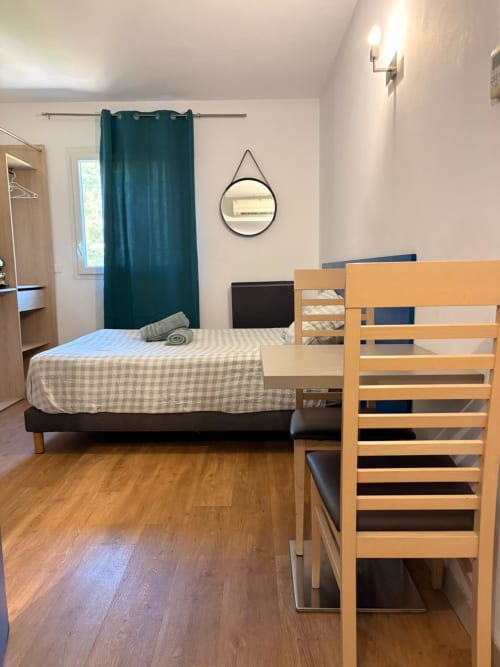 Studio spacieux 305 au Clos d'Aix avec lit en bois, fauteuil, rideaux bleu canard et parquet à Aix-en-Provence