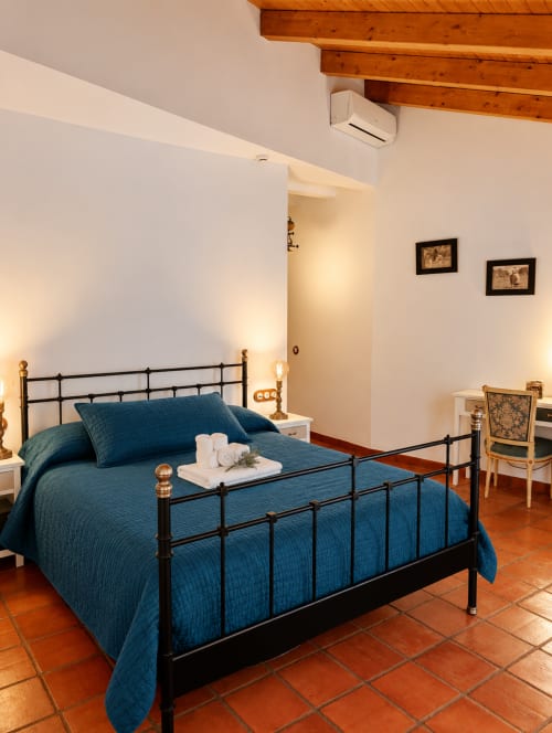 Habitación boutique en El descanso del peregrino con ropa de cama azul, cama de estructura metálica, vigas de madera y vistas a las montañas