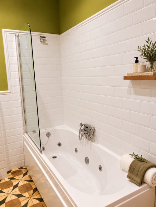 Lujoso baño con tina de hidromasaje, azulejos blancos tipo metro y paredes amarillas en el hotel boutique El descanso del peregrino en Guadalupe