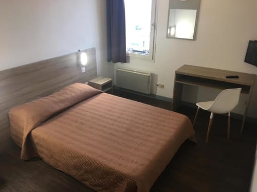 Chambre double à l'Hôtel Motelia à Moissy-Cramayel avec lit, bureau, miroir et fenêtre