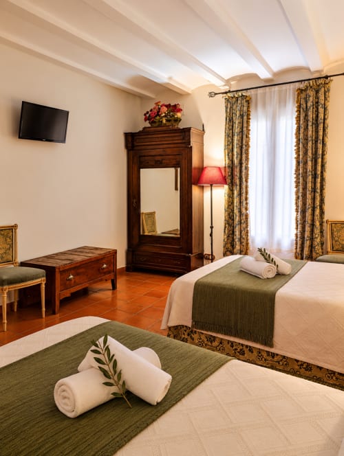 Elegante habitación de boutique hotel en Guadalupe con camas gemelas, armario de madera y decoración clásica