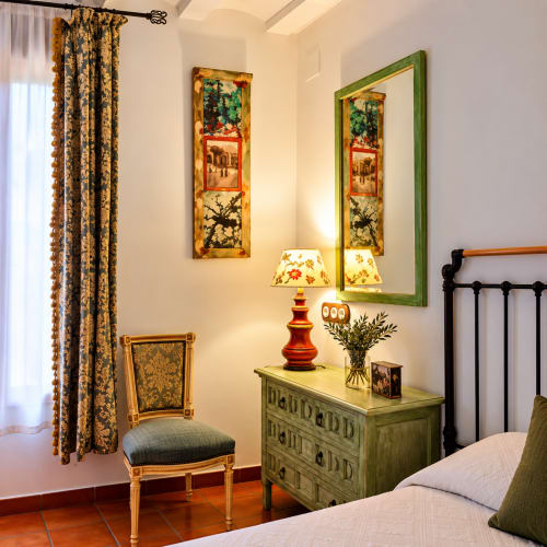 Habitación boutique en El descanso del peregrino de Guadalupe con cómoda verde, espejo, lámpara roja y mobiliario de época