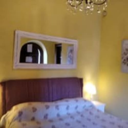 Camera economia dell'Antico Belvedere con pareti gialle, letto con testata bordeaux, specchio e lampada da comodino