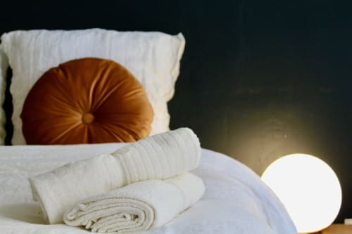 Aménités spa-like dans la salle de bain de Mi Casa Es Su Casa à Carcassonne avec serviettes roulées et coussin décoratif