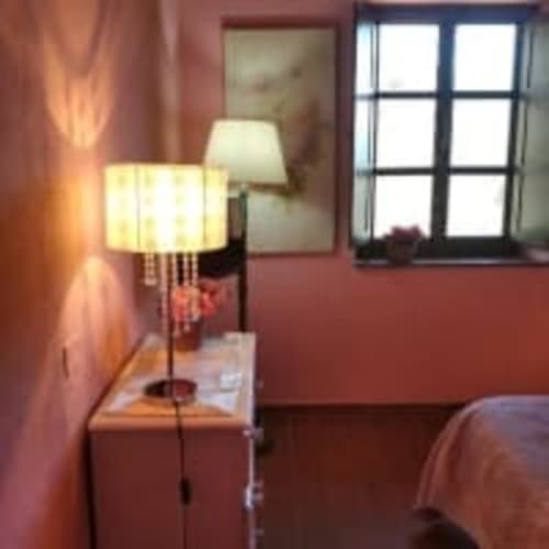 Accogliente angolo camera da letto all'Antico Belvedere con illuminazione calda, elegante lampada da terra e vista giardino dalla finestra