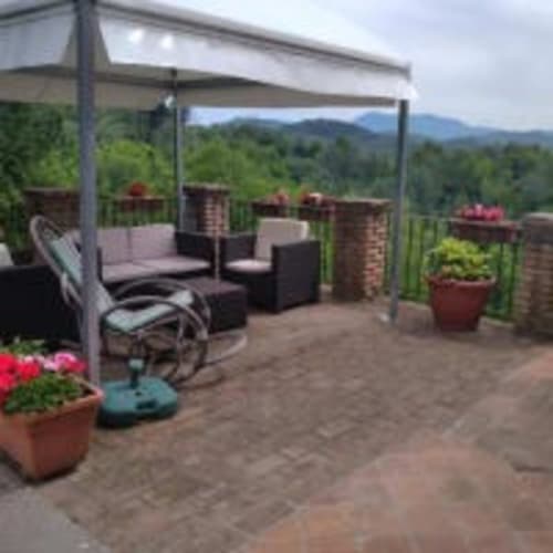 Terrazza del giardino Antico Belvedere con pergolato, area lounge, vasi fioriti e vista montagna