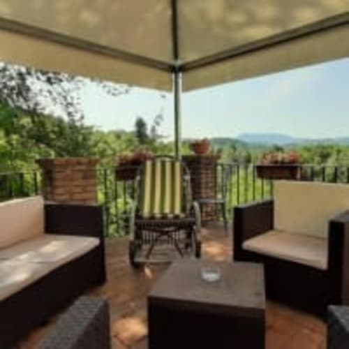 Terrazza Antico Belvedere con area lounge, vista montagna e giardini curati sotto ombrellone beige