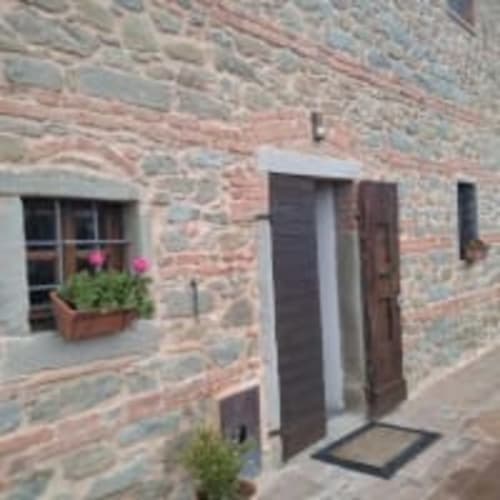 Esterno della casa colonica all'Antico Belvedere B&B con porta in legno, fioriera e vista sul giardino in Italia