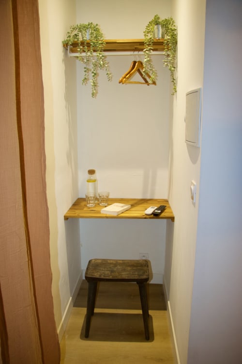 Petit coin vanité du Mi Casa Es Su Casa à Carcassonne avec étagère en bois, plantes, bouteille d'eau et accessoires