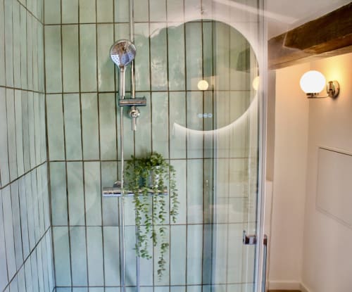 Salle de bain moderne avec carrelage vert métro, pomme de douche pluie et plante retombante à la Suite Choukran