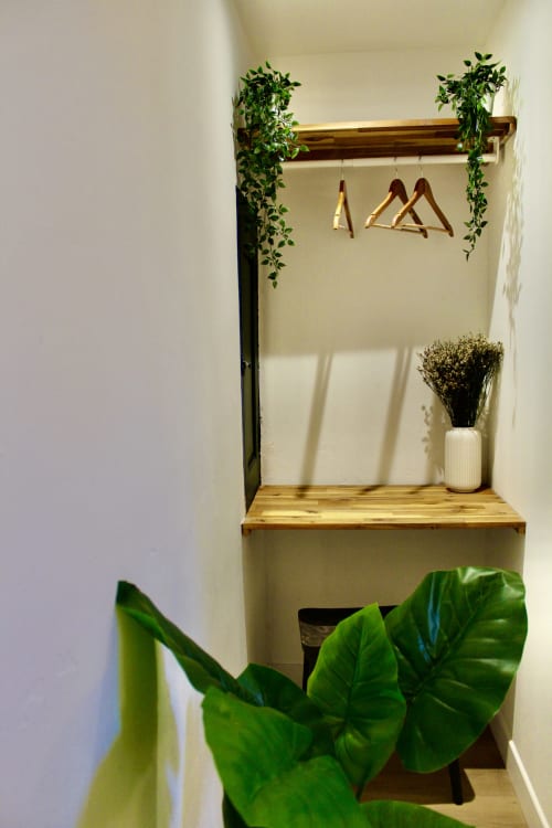 Petit dressing moderne avec tringle en bois, cintres, plantes en pots et fleurs séchées dans la Suite Arigato de Mi Casa Es Su Casa