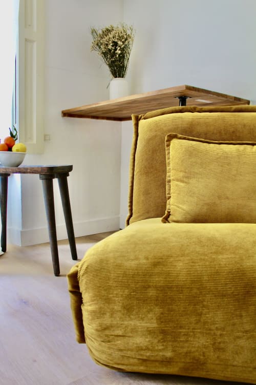 Fauteuil jaune capitonné avec coussins dans la suite Thanks de l'hôtel Mi Casa Es Su Casa à Carcassonne, avec étagère en bois et