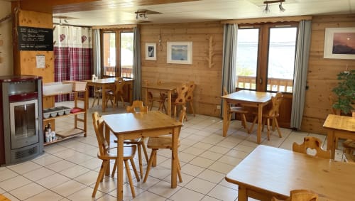 Salle à manger rustique du Chalet De La Yodine avec tables et chaises en bois, décor intérieur de chalet alpin à Feissons sur Salins