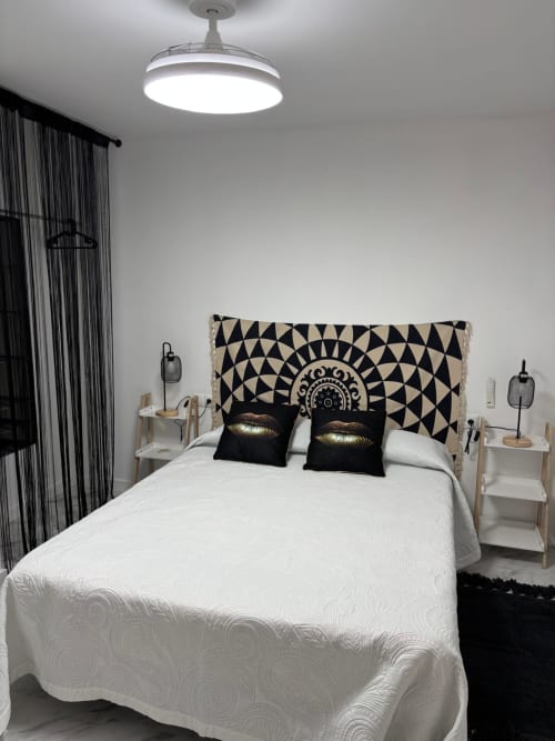 Chambre moderne aux Casonas de Marengo avec tête de lit géométrique, literie blanche, coussins noirs et plafond contemporain