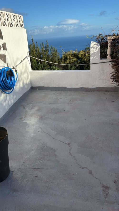 Terrasse sur le toit de Casonas de Marengo avec vue sur l'océan, murs blancs, tuyau bleu et végétation jardin à Icod de los Vinos