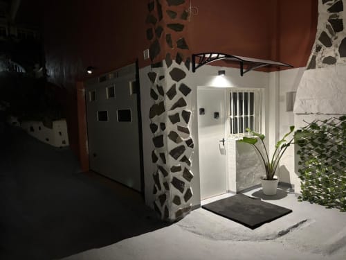 Entrée moderne de l'appartement aux Casonas de Marengo à Icod de los Vinos, avec murs blancs, plantes en pots et jardin