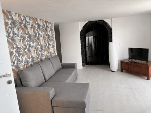 Modern apartment living room at Casonas de marengo with gray sofa, patterned wall art, TV, and sea views in Icod de los Vinos