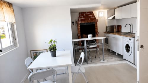 Modern apartment kitchen and dining area with fireplace, white cabinetry, washing machine at Casonas de Marengo, Icod de los