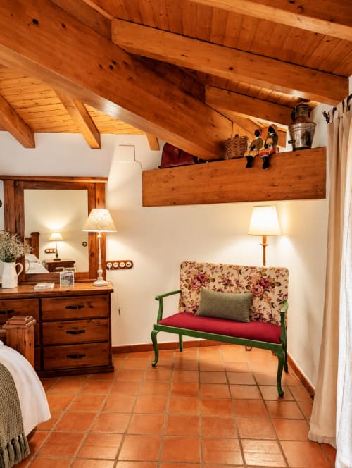 Acogedora habitación boutique en El descanso del peregrino con vigas de madera, suelos de barro y banco verde en Guadalupe