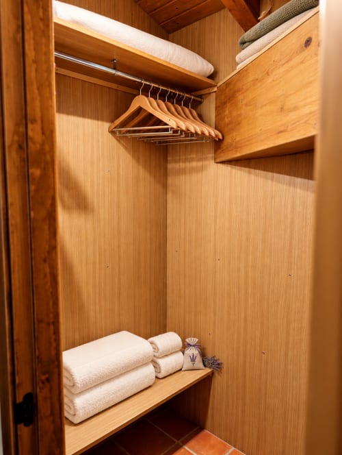 Armario de madera en Habitación Boutique 5 de El descanso del peregrino, Guadalupe, con perchas, toallas y ropa de cama dobladas