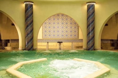 Spa hammam de l'hôtel Eucalyptus Ethnic avec bassin thermal, carrelage géométrique et colonnes ornées à El Ghazouane, Maroc