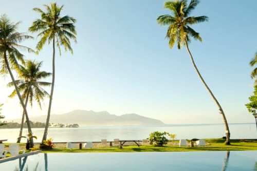 Sublime Tahiti Beach Retreat with pool, palm trees, and mountain views across turquoise waters