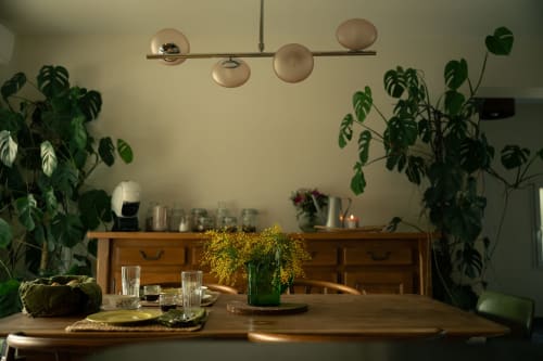 Salle à manger de la Maison d'hôtes Charline à Biganos avec table en bois, luminaires suspendus et plantes verdoyantes