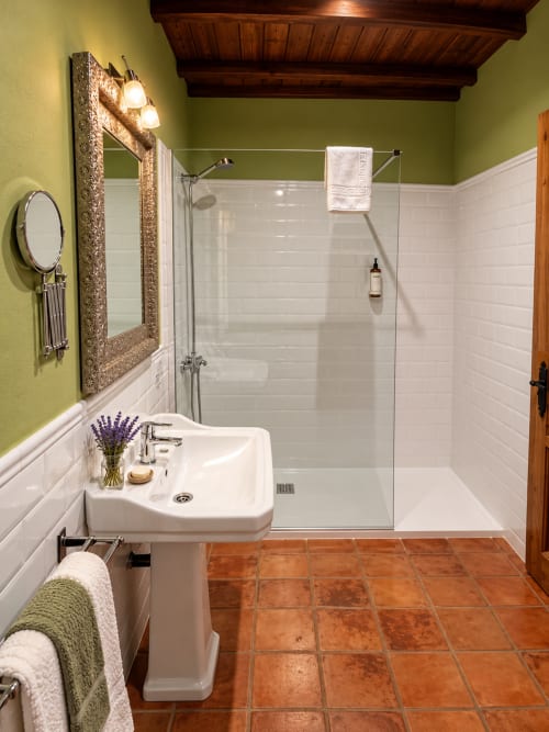Baño moderno en El descanso del peregrino, Guadalape. Azulejos blancos tipo metro, paredes verde lima, ducha de cristal, lavamanos pedestal