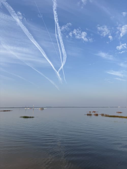 Baie paisible avec voiliers et traînées de condensation à Recevoir par Charline, Biganos