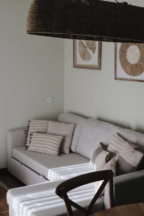 Acogedora habitación en Alojamientos Montaña Leonesa con sofá blanco, cojines rayas y arte botánico en marco en la pared