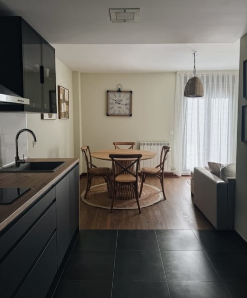 Moderna área de cocina-comedor en apartamento El Mirador del Susarón con mesa redonda, sillas de madera y vistas a la montaña