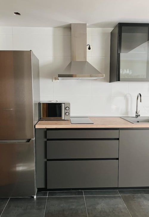 Cocina moderna con electrodomésticos de acero inoxidable, azulejos blancos y encimeras de madera en Alojamientos Montaña Leonesa