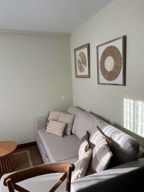 Acogedor dormitorio en Alojamientos Montaña Leonesa con sofá gris, arte textil natural en pared y luz de montaña en El Mirador del