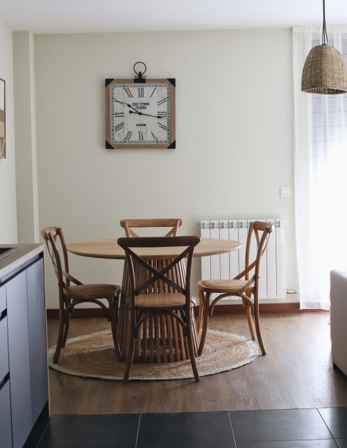 Comedor moderno con mesa redonda de madera, sillas, reloj de pared, lámpara colgante y radiador en El Mirador del Susarón