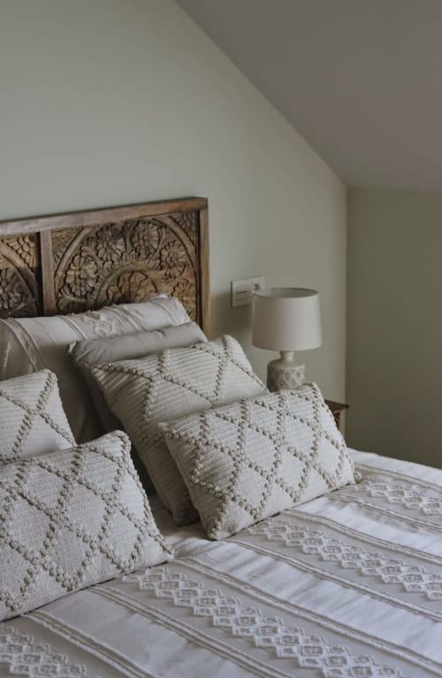 Dormitorio en Alojamientos Montaña Leonesa con cabecera de madera tallada, almohadas acolchadas, ropa de cama blanca y lámpara de mesilla
