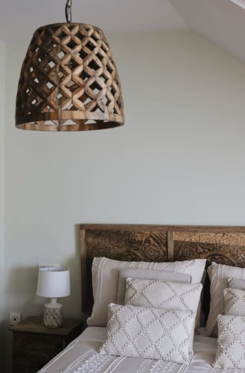 Acogedor dormitorio en Alojamientos Montaña Leonesa con lámpara de madera tallada, cojines decorativos y vistas a la montaña
