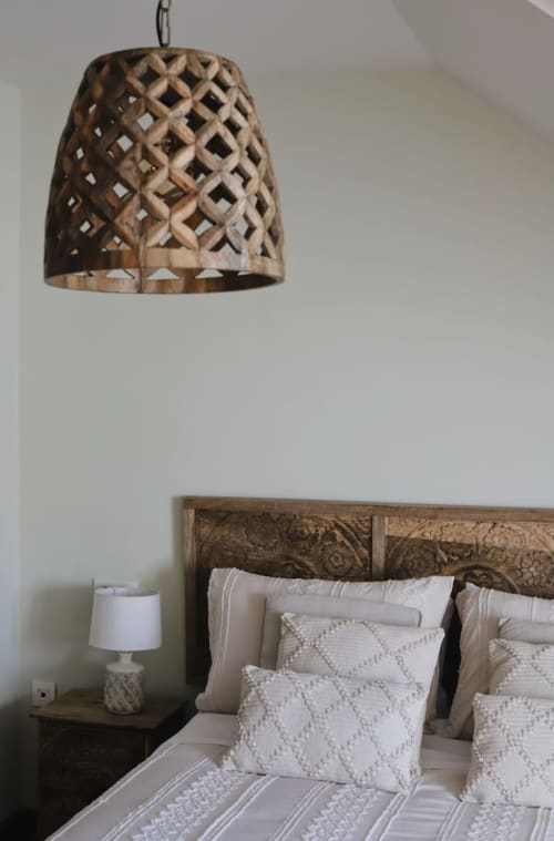 Lámpara colgante de celosía de madera sobre cama con almohadas blancas acolchadas en dormitorio con vistas a la montaña en Alojamientos Montaña Leonesa