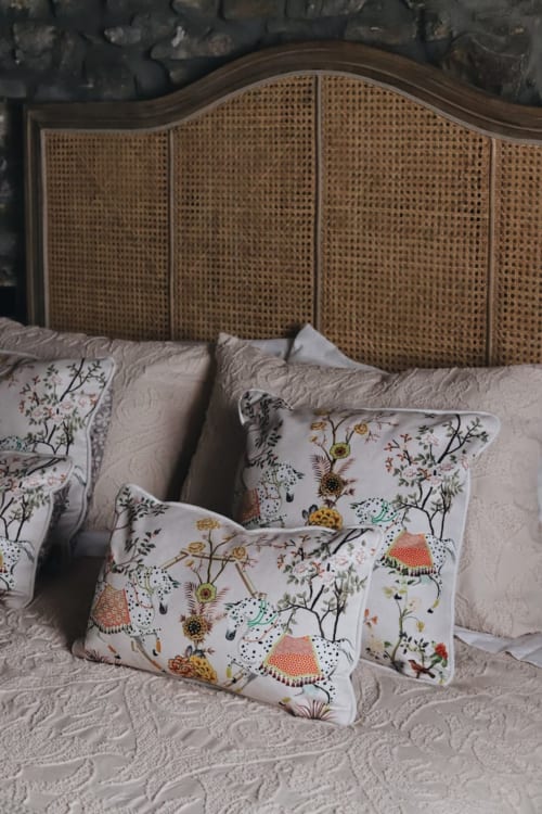 Cama con cabecero de ratán tejido y almohadas con estampado floral en la habitación La Casina de Isoba de Alojamientos Montaña Leonesa