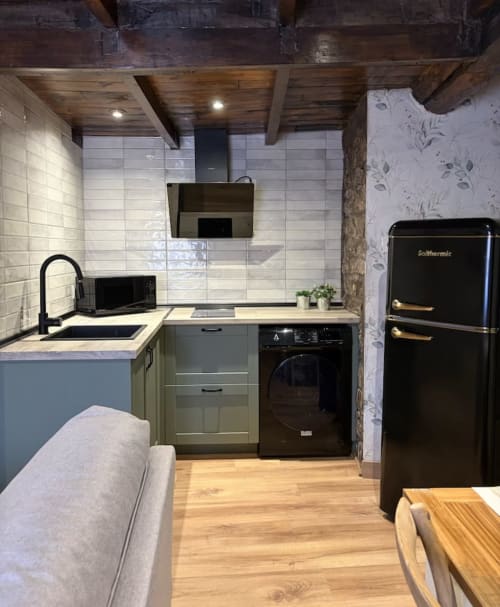 Cocina moderna en La Casina de Isoba de Alojamientos Montaña Leonesa con electrodomésticos negros, muebles en tonos salvia y elementos rústicos
