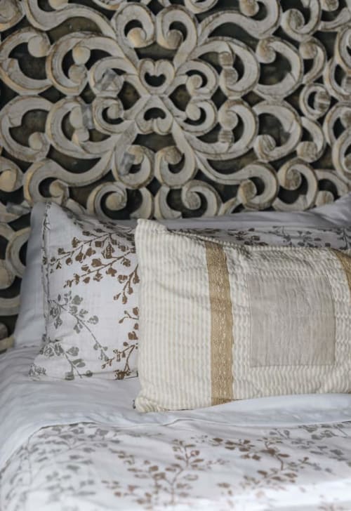 Cojines decorativos en cama con cabecero tallado ornamental en Alojamientos Montaña Leonesa, habitación La Casina de Isoba