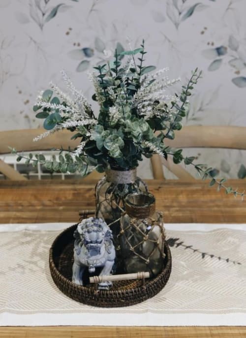 Arreglo floral decorativo con eucalipto y flores blancas en cesta tejida en Alojamientos Montaña Leonesa