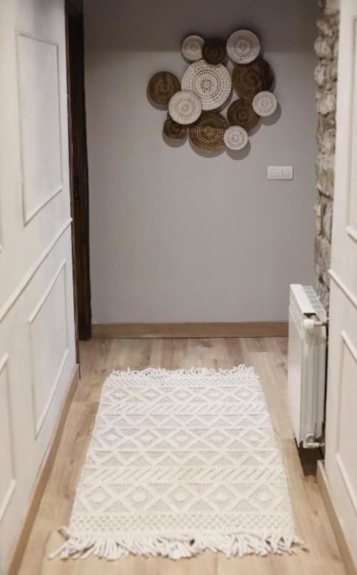 Pasillo de Alojamientos Montaña Leonesa con platos decorativos tejidos y alfombra geométrica blanca