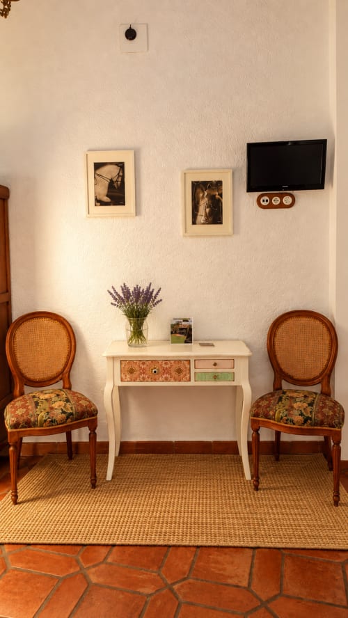 Habitación boutique en El descanso del peregrino en Guadalupe con sillas vintage, escritorio y fotografías enmarcadas en paredes color crema