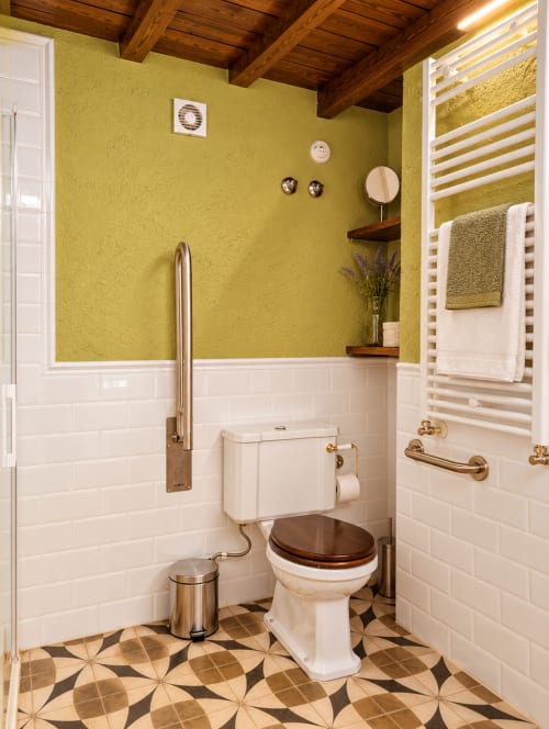 Baño luminoso en amarillo y blanco con vigas de madera, azulejos metro, piso con patrón y características de accesibilidad en El descanso