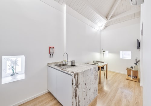 Cozinha moderna no apartamento Oporto Comfort Dom Hugo Porto com ilha em mármore, paredes brancas, claraboias e madeira