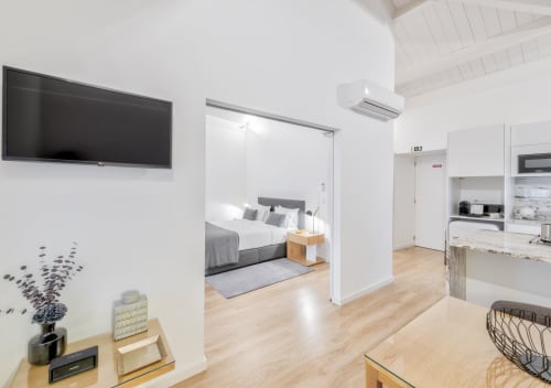 Modern studio apartment at Oporto Comfort Dom Hugo with open-plan kitchen, living area, and bedroom view with flat-screen TV