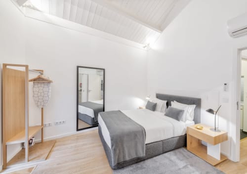 Modern bedroom at Oporto Comfort Dom Hugo Porto with gray bed, wooden furniture, and skylight ceiling