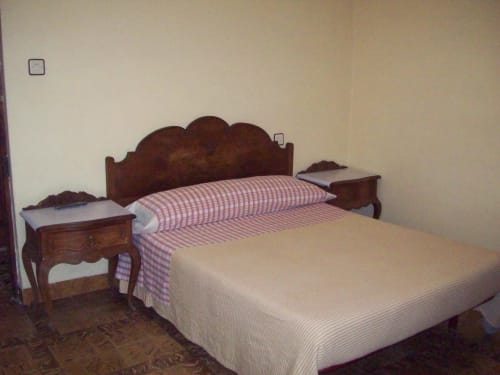 Habitación doble estándar en Pensión Los Pinos Gijón con cama de madera y ropa de cama a rayas